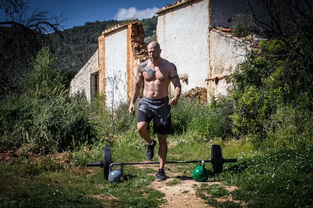 Mężczyzna biegnący w kierunku sztangi i odważników kettlebell na trawie