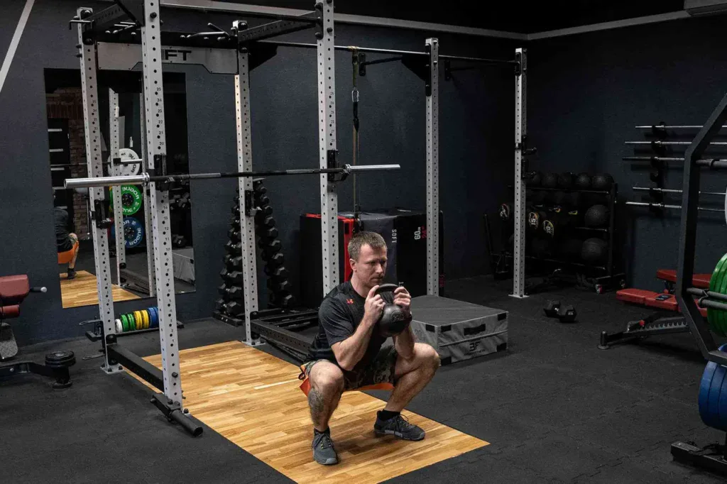 Goblet squat z kettlebellem w klatce treningowej