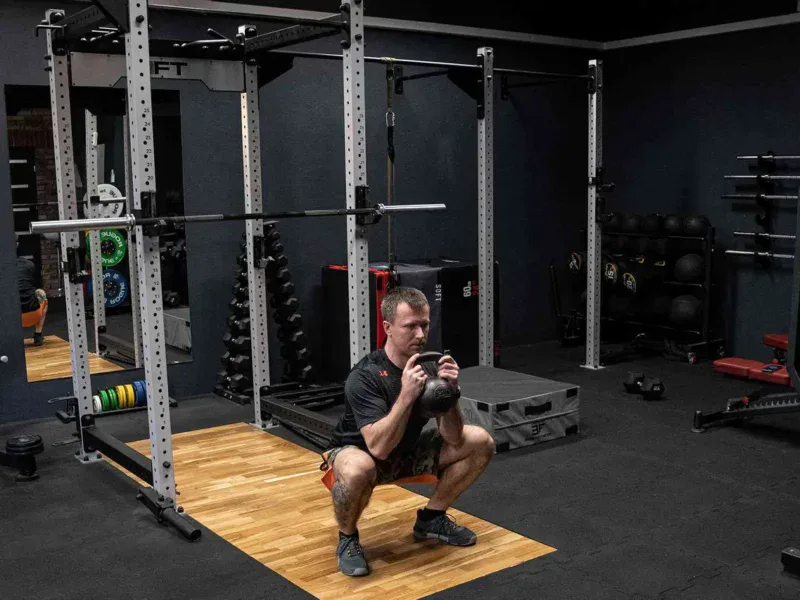 Goblet squat z kettlebellem w klatce treningowej