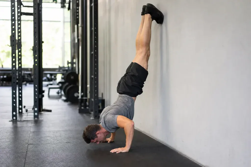 Mężczyzna w dolnej fazie handstand push up przy ścianie