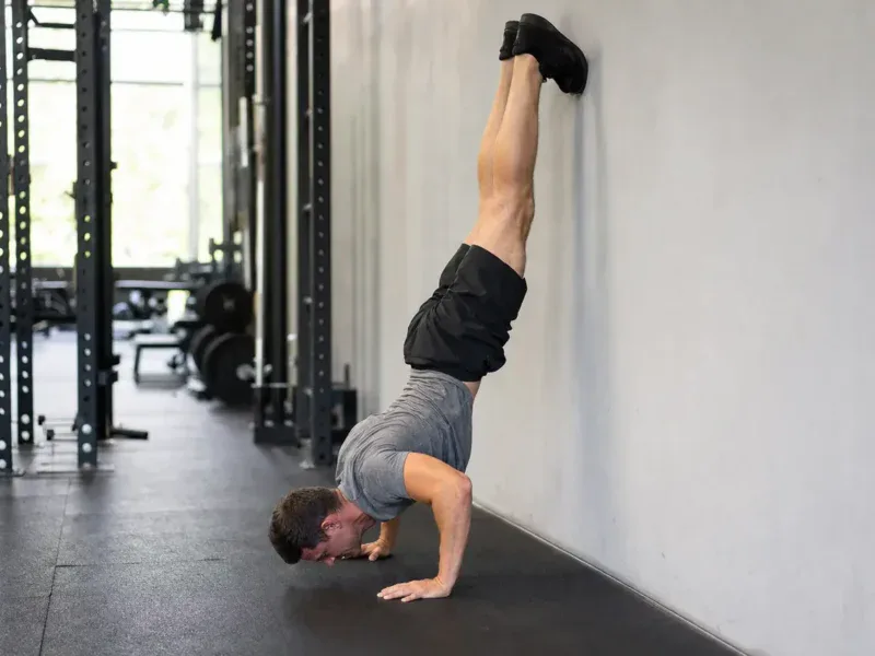 Mężczyzna w dolnej fazie handstand push up przy ścianie